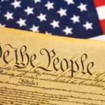 a photo of the US Constitution next to a US flag